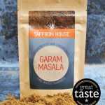 Aromatic Garam Masala spice blend in a container on a wooden surface