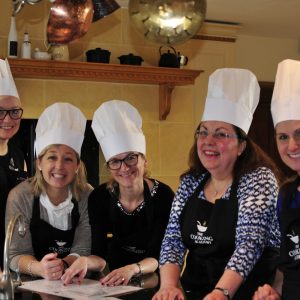 group of women at the kitchen happy wearing hats